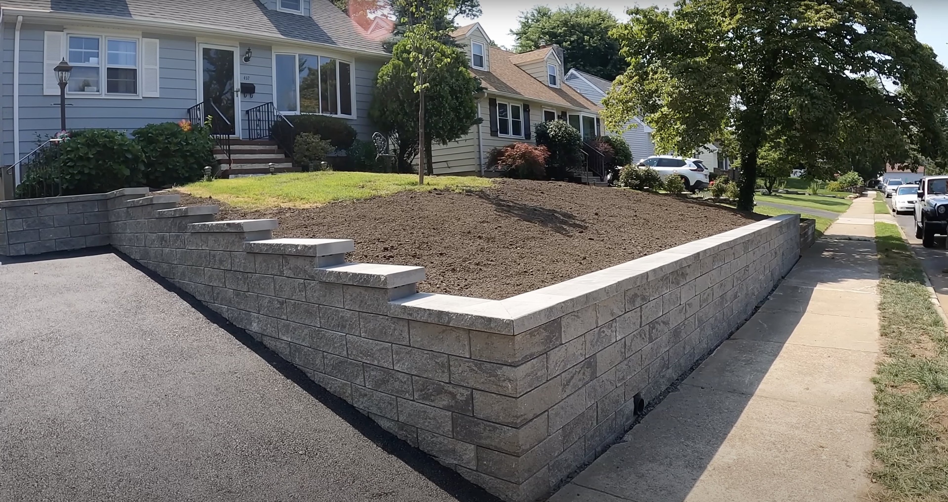 Newly constructed concrete retaining wall with professional finishing in residential setting