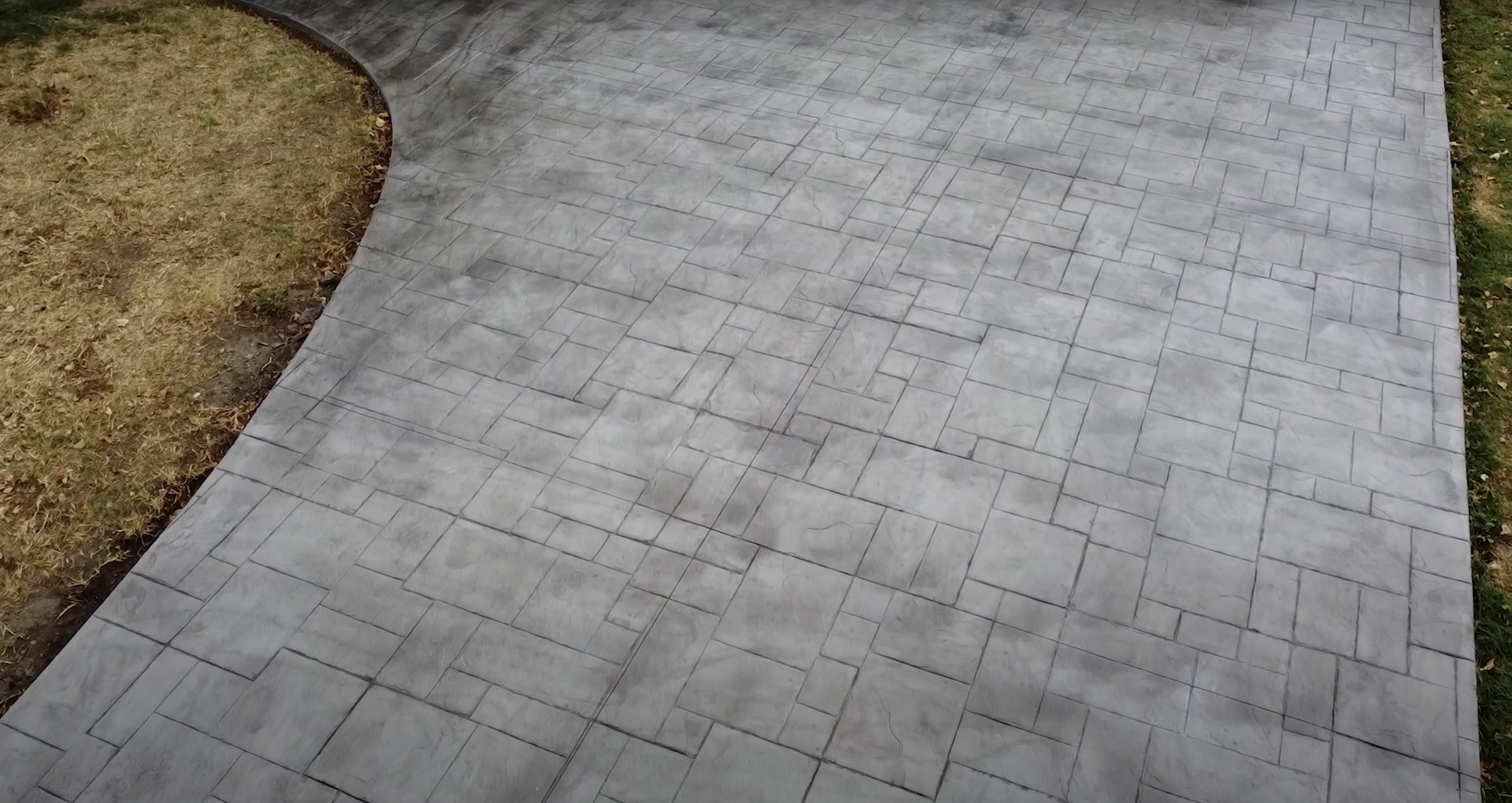 Stamped concrete walkway with herringbone brick pattern