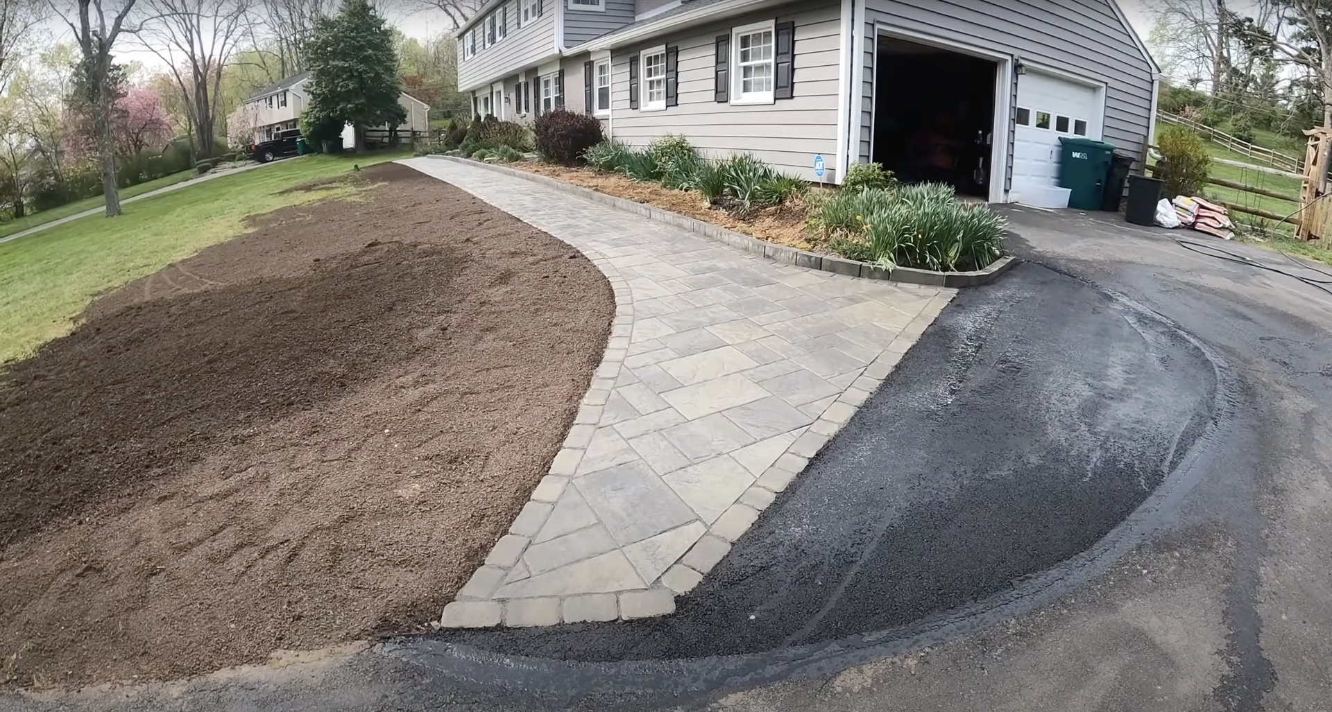 Curved concrete walkway and paver installation around residential property